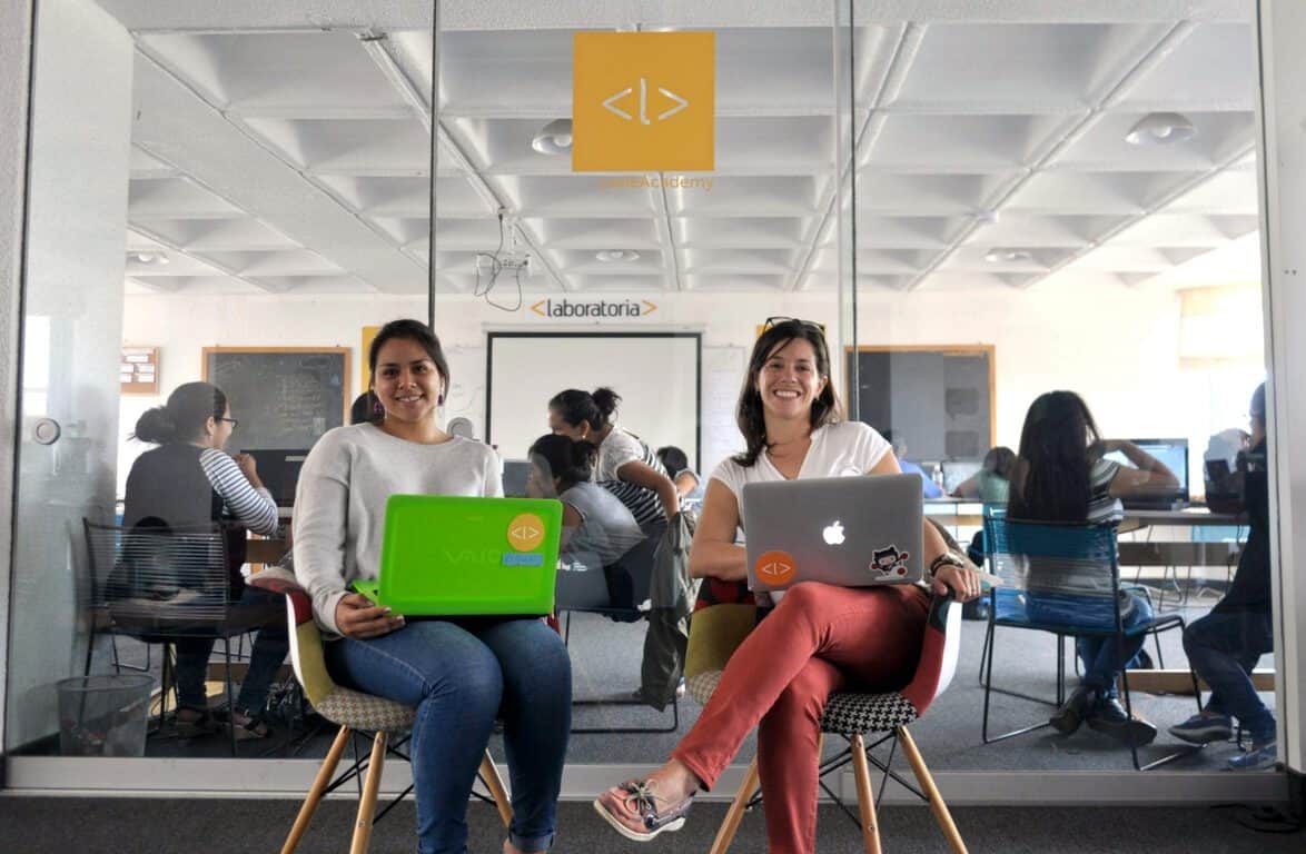 Reina Torrejon poses with Laboratoria regional director Ana Maria Martinez in front of the classroom where she and her classmates are learning front-end web development.