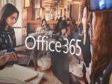Image of reflection on glass showing people working with Microsoft devices with "Office 365" text