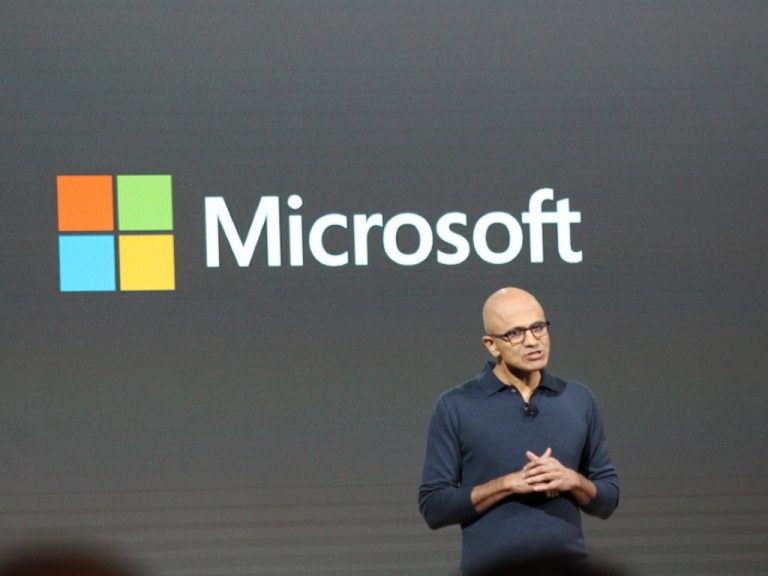 Satya nadella onstage with microsoft logo