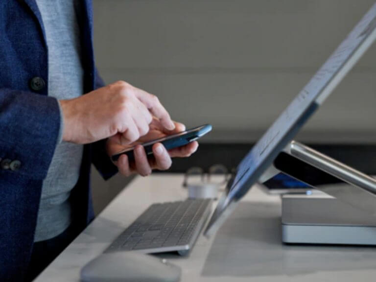 person with a smartphone and Surface Studio